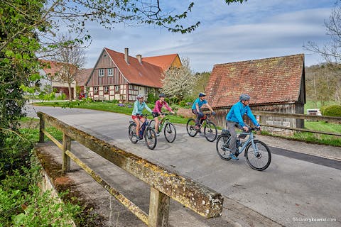 Eine Gruppe Radfahrer fährt an einem Bauernhof vorbei
